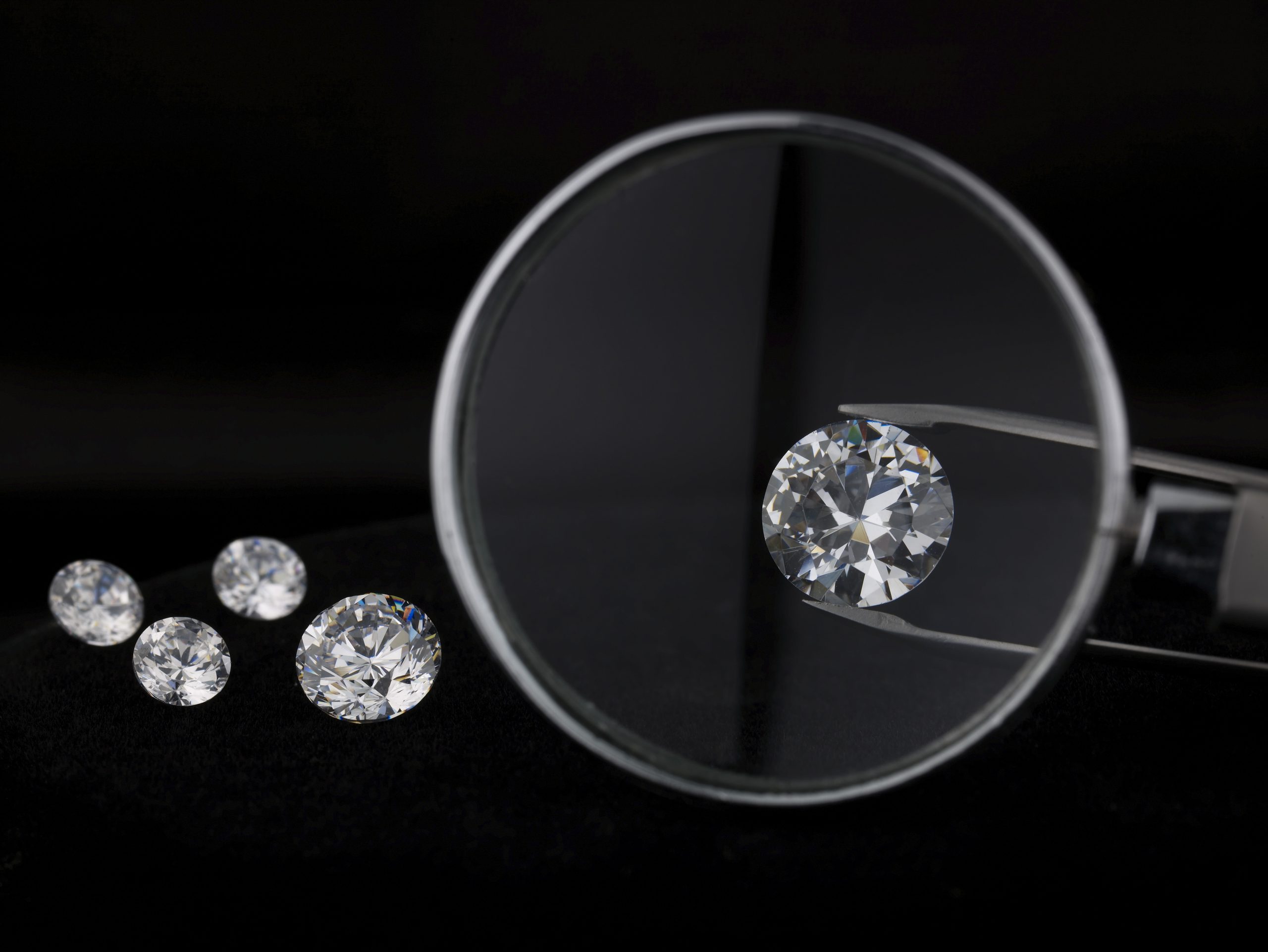 A loose lab-grown diamond held with tweezers under a loupe